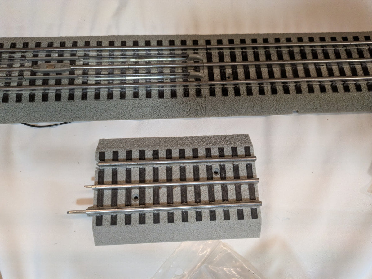 Two used Lionel 6-12040 FasTrack transition pieces showing exposed tubular-track pins