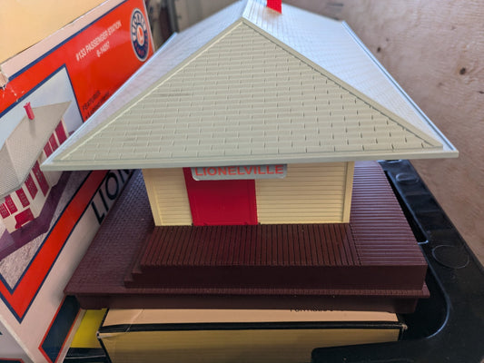 Lionel 6-14257 #133 Passenger Station front three-quarter view with cream walls, red doors, gray roof, and brown base