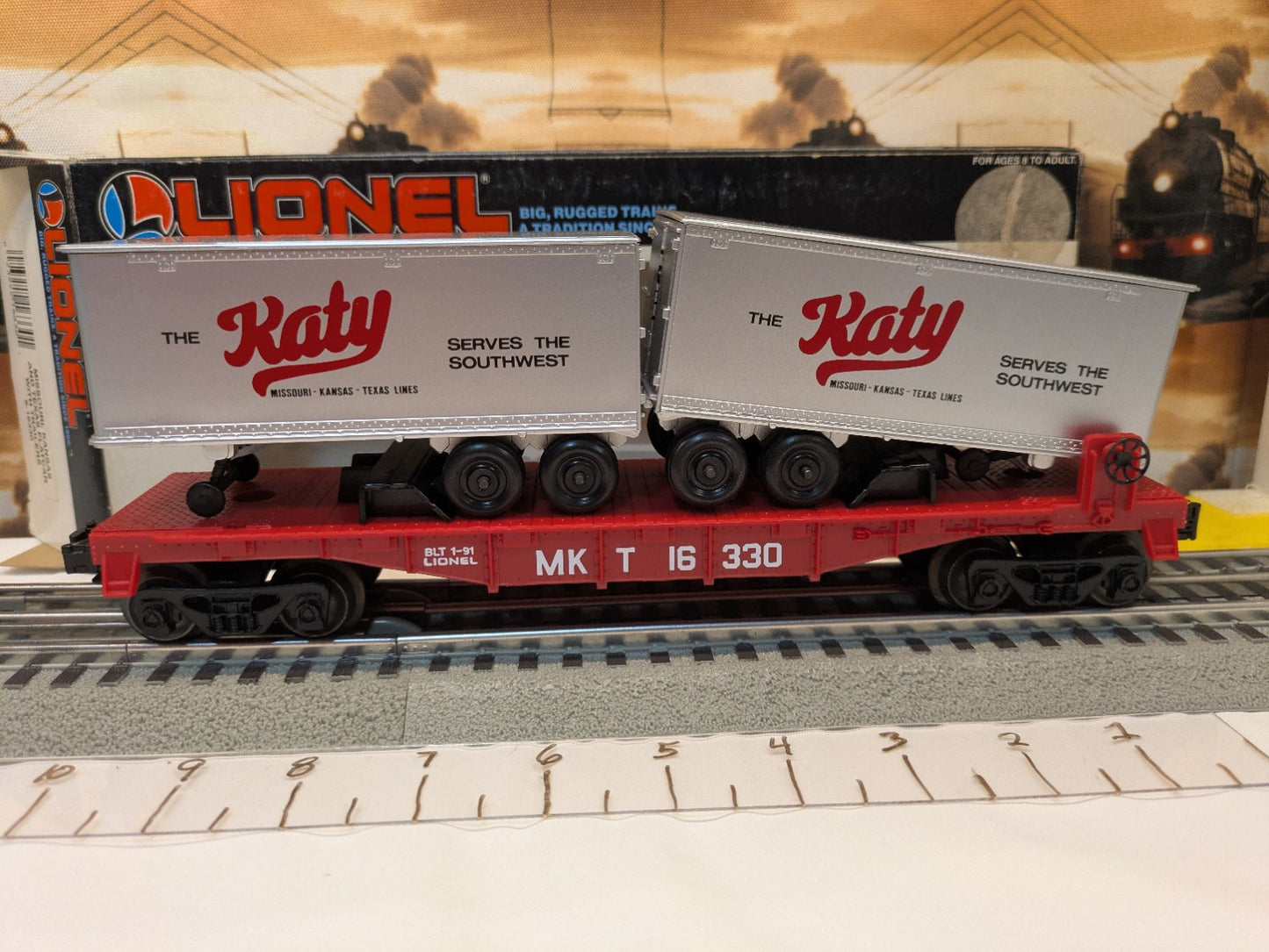 Broadside view of Lionel 6-16330 Katy flatcar carrying two silver trailers
